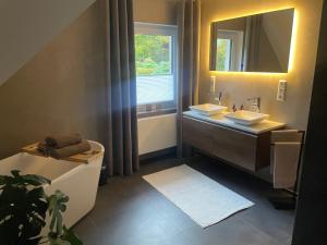 a bathroom with two sinks and a mirror and a tub at Ferienwohnung Lang in Nümbrecht +17 photos