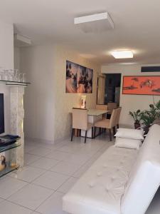 ein Wohnzimmer mit einer weißen Couch und einem Tisch in der Unterkunft Quarto Individual para 3 Pessoas em AP Compartilhado in João Pessoa