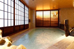 a large indoor pool in a room with windows at Dormy Inn Nagano in Nagano