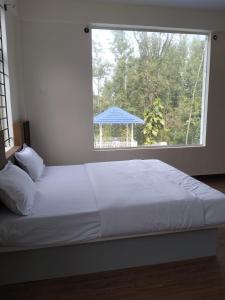ein Bett in einem Schlafzimmer mit einem großen Fenster in der Unterkunft Aetheria Estate Retreat in Chikmagalur