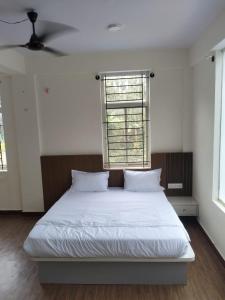 ein Schlafzimmer mit einem Bett mit weißen Laken und einem Fenster in der Unterkunft Aetheria Estate Retreat in Chikmagalur