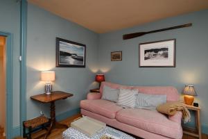a living room with a pink couch and a table at Pilots House Aldeburgh in Aldeburgh