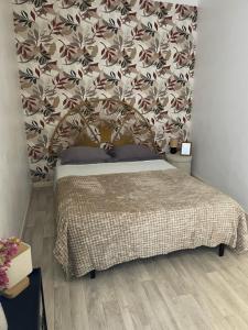 a bedroom with a bed with a floral wall at Studio calme au centre-ville in Manosque