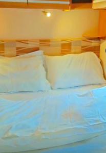 1 cama con almohadas blancas y cabecero en كرفان لحظة لقاء, en Al Ula