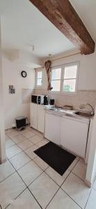 eine Küche mit weißen Schränken und einem Fliesenboden in der Unterkunft Montagnard RDC Hyper centre in Chartres + 4 Fotos