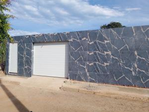 a garage with a white garage door and a stone wall at casas em búzios 8 in Búzios