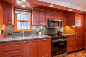 eine Küche mit Holzschränken, Spüle und Mikrowelle in der Unterkunft Cedar Crest - Robin Cottage 6 in Homewood + 16 Fotos