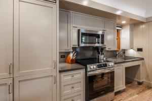 eine Küche mit weißen Schränken und einem Herd mit Backofen in der Unterkunft Cedar Crest - Sparrow Cottage 1 in Homewood