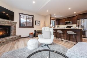 a living room with a fireplace and a white chair at Mountainside 15 in Mammoth Lakes