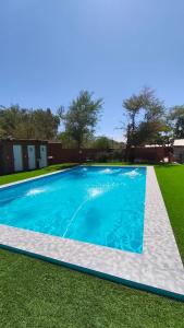 a swimming pool with blue water in a yard at Hostal Ribera de Quitor in San Pedro de Atacama +5 photos