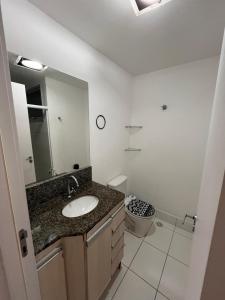 une salle de bain avec un lavabo, des toilettes et un miroir dans l'établissement Quarto apartamento em Guarapari, à Guarapari