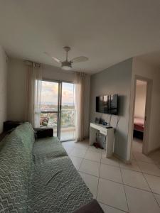 une chambre avec un lit, une télévision et une fenêtre dans l'établissement Quarto apartamento em Guarapari, à Guarapari