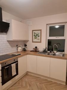 eine Küche mit weißen Schränken und einer Spüle und einem Fenster in der Unterkunft Central Park View - Modern & Stylish 2 Bed Apartment - Great Location in Scunthorpe