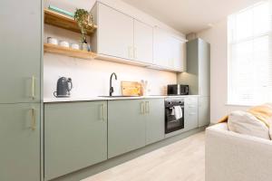 a kitchen with white cabinets and a sink at Apartment Ten Pelican House in Bournemouth
