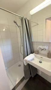 a white bathroom with a shower and a sink at Lea Apartement - Ruhiges Studio in Schaffhausen