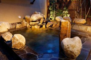 a pool of water with rocks in a backyard at Dormy Inn Nagano in Nagano