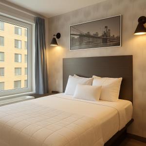 ein Schlafzimmer mit einem großen weißen Bett mit einem Fenster in der Unterkunft Bkway Hotel Brooklyn in Brooklyn