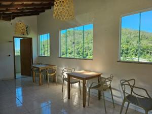 two tables and chairs in a room with windows at Villa Sol hospedaria in Paty do Alferes