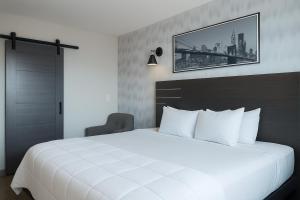 a bedroom with a large white bed with a picture on the wall at Bkway Hotel Brooklyn in Brooklyn