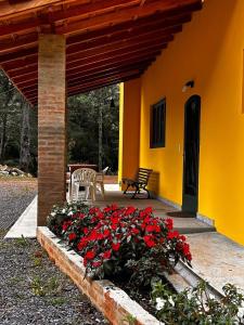 a porch of a house with a bunch of red flowers at Casa Aquarius in Camanducaia
