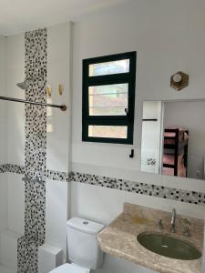 a bathroom with a toilet and a sink and a window at Casa Aquarius in Camanducaia +34 photos
