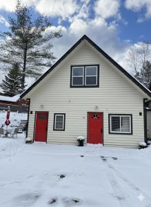 una casa con puertas rojas en la nieve en Modern Home &Cozy, en Lake Placid