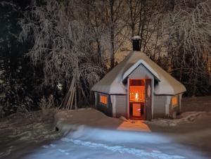 a small gingerbread house in the snow at night at Arctic Aurora Villa with a Lappish Grill Hut - Northern Lights and Private Sledding Hill in the Backyard, in the Hometown of Santa Claus, Rovaniemi in Rovaniemi