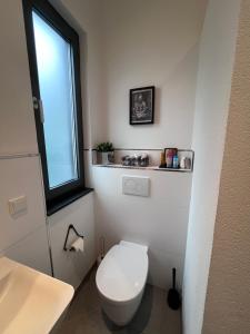 Un baño con inodoro blanco y ventana. en Modernes Tiny Apartment in Lage, en Lage 31 fotos más