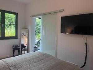 Un dormitorio con una cama con un televisor en la pared. en Modernes Tiny Apartment in Lage, en Lage