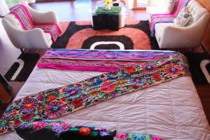 a blanket on a bed in a room with chairs at Titicaca SUMA SARTIRI in Puno