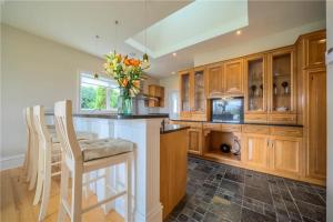 - une cuisine avec des placards en bois et un vase de fleurs dans l'établissement Tomies House, à Laune Bridge