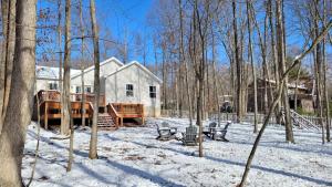 a house with a deck in the snow at The Hideaway House in Swanton