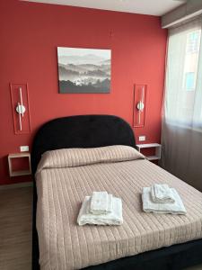 a bedroom with red walls and a bed with towels on it at SeaDoor in Livorno