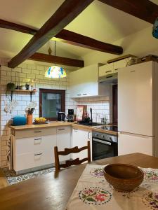 a kitchen with a table and a white refrigerator at Kućice za odmor Šalatin jarek - Free tickets to local attractions in Ðurđevac