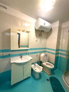 Un baño con lavabo, inodoro y espejo. en Ergi’s Host Apartment, en Tirana 4 fotos más