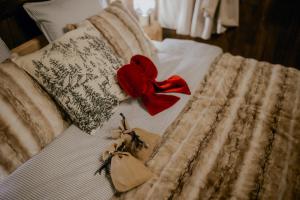 een bed met een rode strik en twee voorwerpen erop bij Na Gorczańskim Wierchu, sauna i balia na wyłączność in Rabka