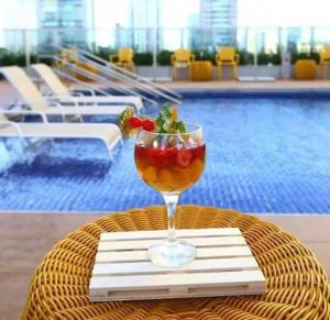 a drink in a glass on a table near a pool at Transamérica Executive Campos dos Goytacazes in Campos dos Goytacazes