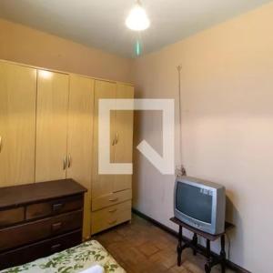 a bedroom with a tv and a bed and a dresser at Apartamento 04 old no Capão da Imbuia in Curitiba