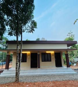 una casa con dos árboles delante de ella en Cosy Stays, 2 Adjacent Apartments in Irinjalakuda, en Irinjālakuda