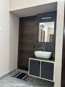 Un baño con lavabo y puerta de madera. en Cosy Stays, 2 Adjacent Apartments in Irinjalakuda, en Irinjālakuda
