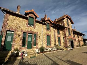 un grand bâtiment en briques avec des portes et des fenêtres vertes dans l'établissement Le Manoir du Bonheur, à Chaumes-en-Brie