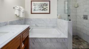 une salle de bain blanche avec une baignoire et une douche dans l'établissement 1117 Lodge At Spruce Peak Ski In Ski In Ski Out King Studio By Stowe Mountain Rentals, à Stowe 12 autres photos