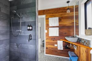 a bathroom with a wooden wall and a sink at The Hideout in Mangawhai