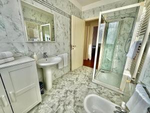 ein weißes Badezimmer mit Waschbecken und Dusche in der Unterkunft Appartamento con posto auto riservato tra spiaggia, centro, stazione ed ospedale in Pescara + 12 Fotos