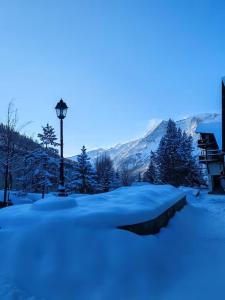a snow covered street with a light pole and trees at Rifugio delle Emozioni in Grange Sises