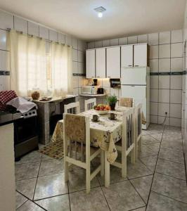 a kitchen with white cabinets and a table with chairs at Hostel Londrina in Londrina