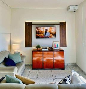 a living room with a couch and a tv on a wall at Hostel Londrina in Londrina