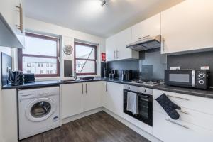 a kitchen with white cabinets and a washer and dryer at Fraserburgh Apartment - 2 bed, free parking & wifi in Fraserburgh