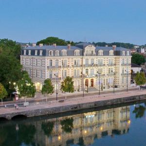 un grande edificio accanto a un corpo idrico di Les Jardins du Mess a Verdun-sur-Meuse