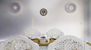 a table with white chairs and plates on the wall at Djerba Dar Iyad in Mezraya